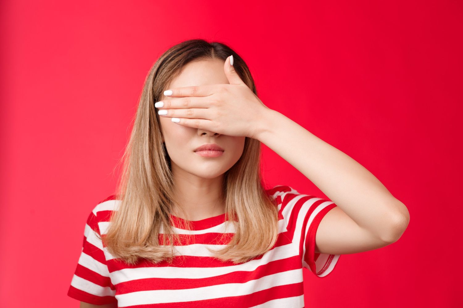junge Frau versteckt ihr Gesicht hinter ihren Händen